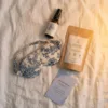 Ocean Mind box contents laid out on white bedding: pillow mist, rooibos tea, sleep mask and reflection card